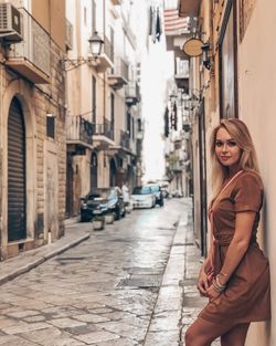 Portrait of smiling young woman standing on street in city