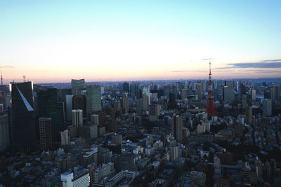 Aerial view of buildings in city against clear sky during sunset