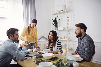 Woman pouring champagne for friends in party at home