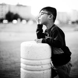 Side view of boy wearing eyeglasses by bollard on street