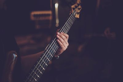 Cropped hand of man playing guitar in darkroom