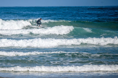 Man surfing in sea against sky