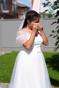 Bride wiping eyes during wedding ceremony