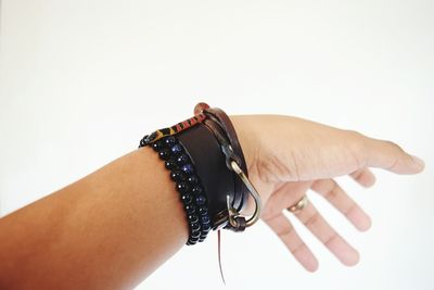 Cropped hand wearing bracelets against white background