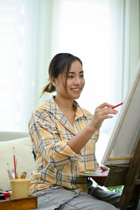 Portrait of young woman using mobile phone at home