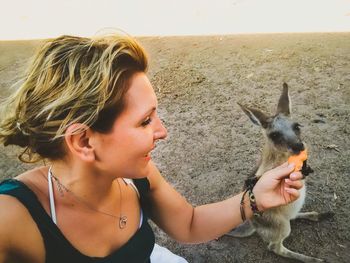 Young woman feeding kangaroo on field