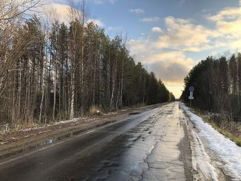 Road amidst trees in forest against sky