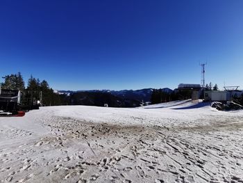 Snow covered land against clear blue sky