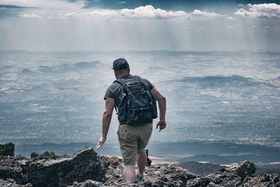 Rear view of man looking at sea against sky