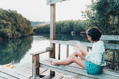 Woman sitting on chair by lake