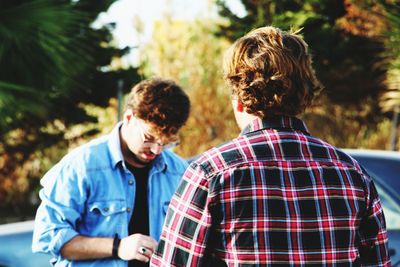 Male friends standing against trees