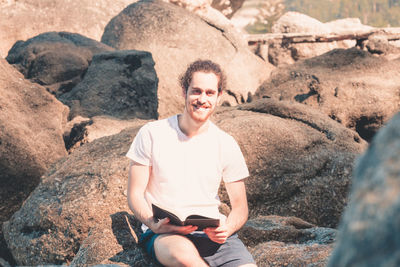 Young man sitting on rock