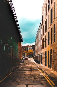 Empty road amidst buildings in city against sky