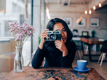 Close-up portrait of woman holding coffee cup on table