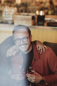 Woman leaning on male friend while having wine in bar during dinner party