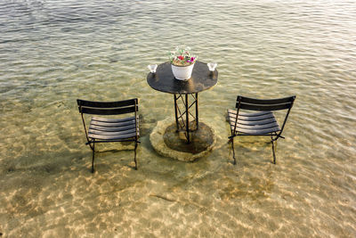 High angle view of chairs and table on sea