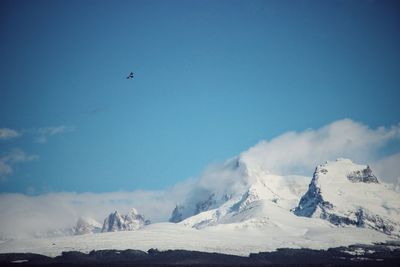 Low angle view of snowcapped mountains against blue sky