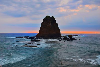 Scenic view of rocks in sea against sky during sunset