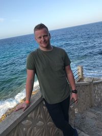 Portrait of smiling man standing by sea against sky