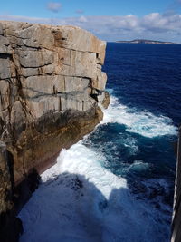 Scenic view of sea by cliff against sky