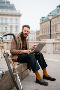 Smiling businessman using laptop outdoors