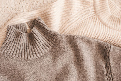 Knitted woolen beige and gray sweaters top view.