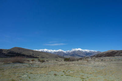 Scenic view of arid landscape against blue sky