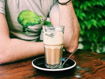 Midsection of man with drink on table