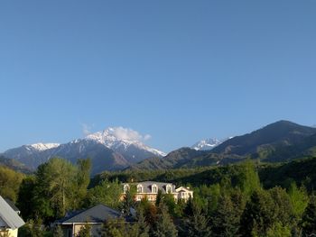 Houses and mountains against clear blue sky