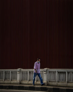 Full length of man standing against railing in city