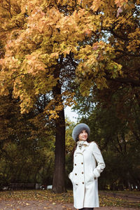 Beautiful girl in a coat and a fur hat on an autumn landscape