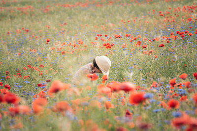Girl with hat walking in the middle of a poppy field