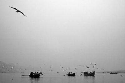 Boats in calm lake against clear sky