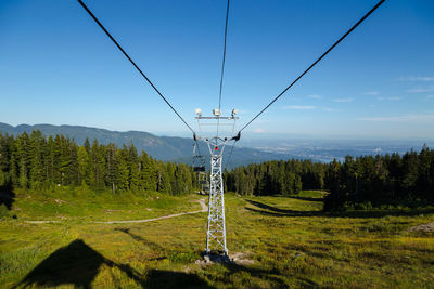 Overhead cable car on landscape against sky