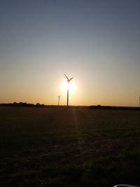 Wind turbines on field against sky during sunset