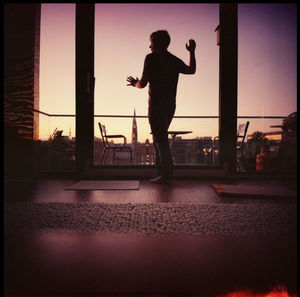 Silhouette man standing on street against sky during sunset