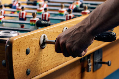 Crop unrecognizable african american male playing table soccer game while entertaining at weekend