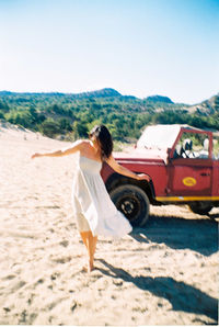 Young woman on sand at beach against sky