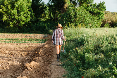 Rear view of man walking on dirt road