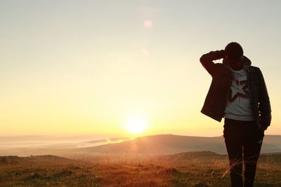 Silhouette man walking on mountain against sky during sunrise