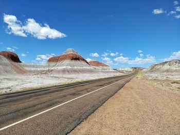 Road leading towards mountains against sky