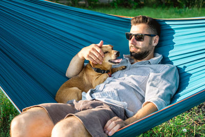 Cute little dog is yawing. resting of dog with his owner in hammock on sunny summer day.