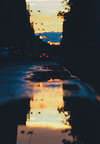 Illuminated city street against sky at sunset