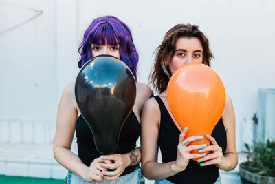 Portrait of women holding balloons while standing on land