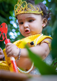 Adorable infant dressed as hindu god krishna cute facial expression playing at tree at janmashtami