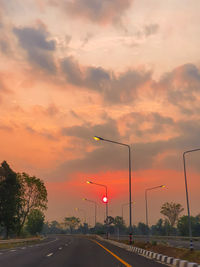 Cars on street against sky during sunset