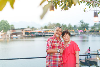 Portrait of couple standing against lake