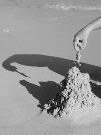 Close-up of hand playing with sand at beach