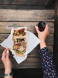 High angle view of woman holding drink while having food on table