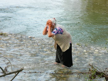 High angle view of woman washing face while standing in river